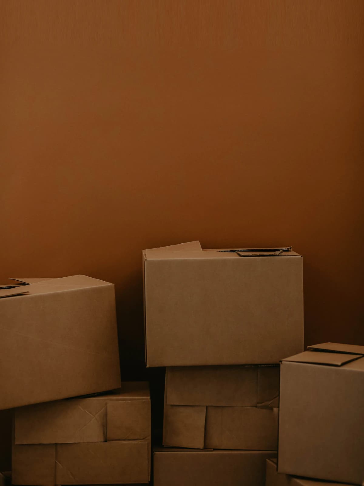 Kraft parcel boxes stacked against a warm terracotta wall
